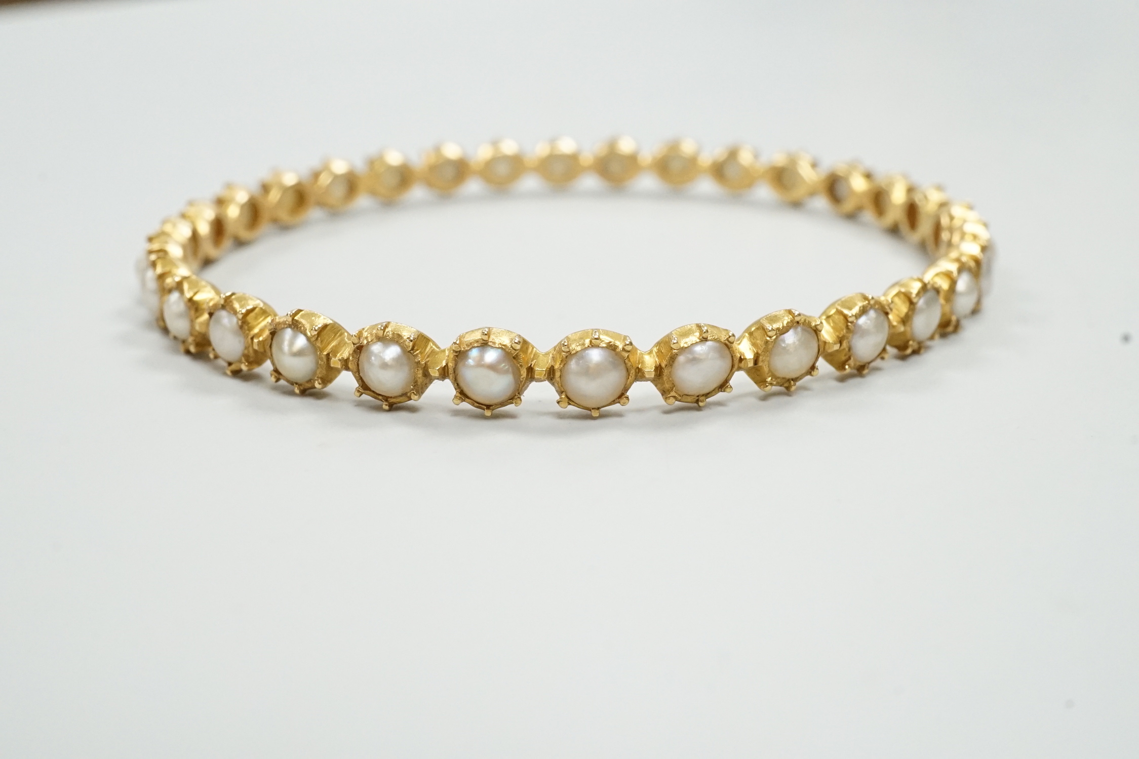 A modern yellow metal and split pearl set bangle, interior diameter approx. 58mm, gross weight 13.7 grams.